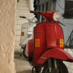 a red scooter parked next to a white scooter